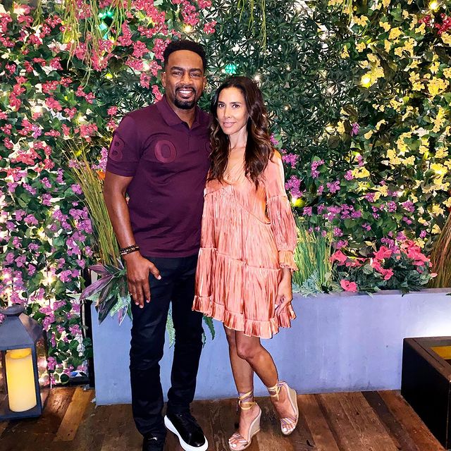 Kristen Baker Bellamy in a glittered pink dress with her husband in a purple t-shirt and black pants.